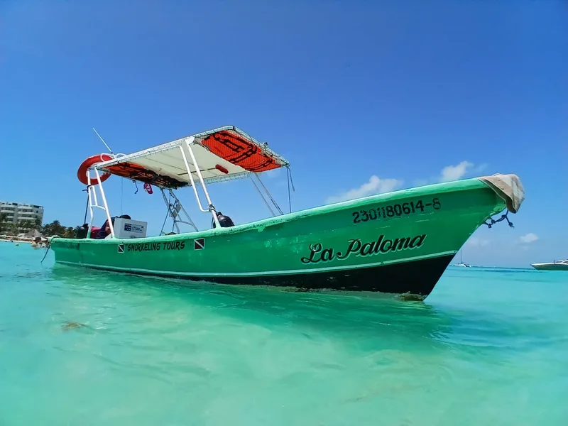 Lancha verde La Paloma en el agua turquesa de Isla Mujeres