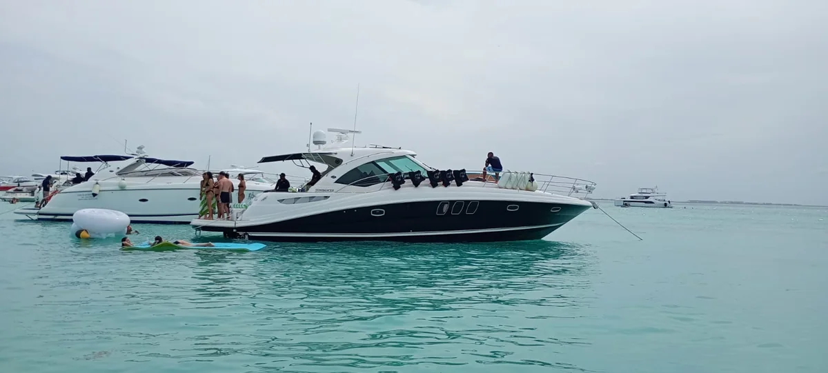 Yate anclado en aguas turquesa con clientes nadando en Isla Mujeres
